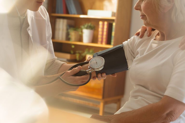 Young doctor measuring the blood pressure to her senior patient